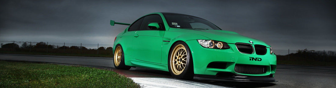 IND Green Hell BMW E92 M3 on track approaching apex with red and white curbing shown from front passenger-side angle