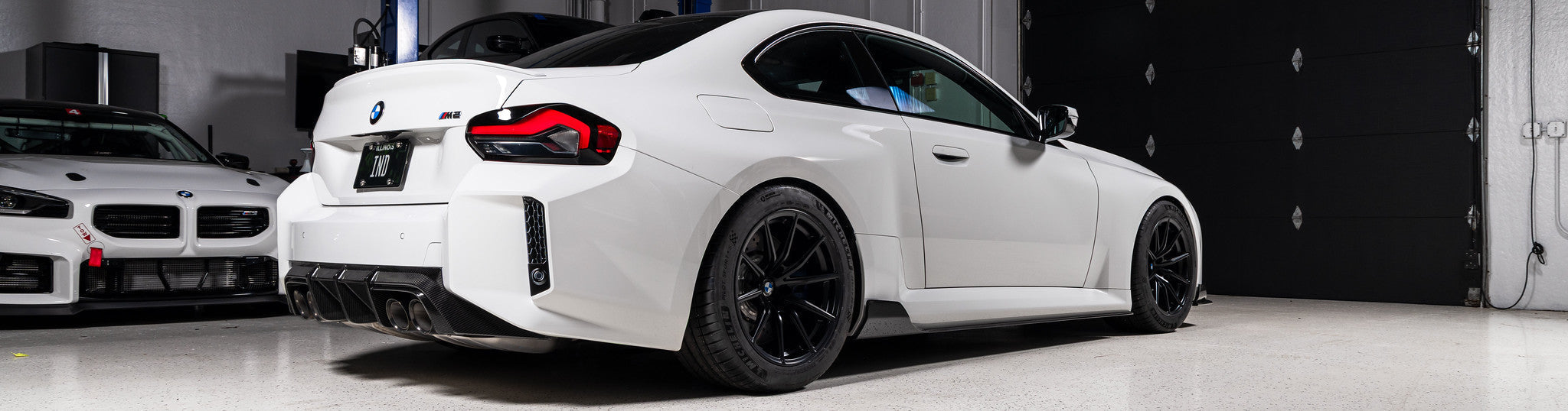 Alpine White BMW G87 M2 rear view featuring Acexxon Full Replacement Rear Reflector Inserts with honeycomb design and gloss black finish