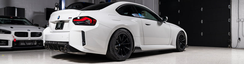 Alpine White BMW G87 M2 rear view featuring Acexxon Full Replacement Rear Reflector Inserts with honeycomb design and gloss black finish