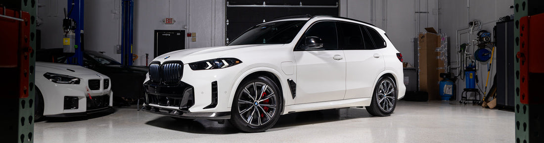 Alpine White BMW G05 X5 with Baan Velgen Airmatic Lowering Link Set installed, demonstrating reduced ride height and improved stance in the IND warehouse