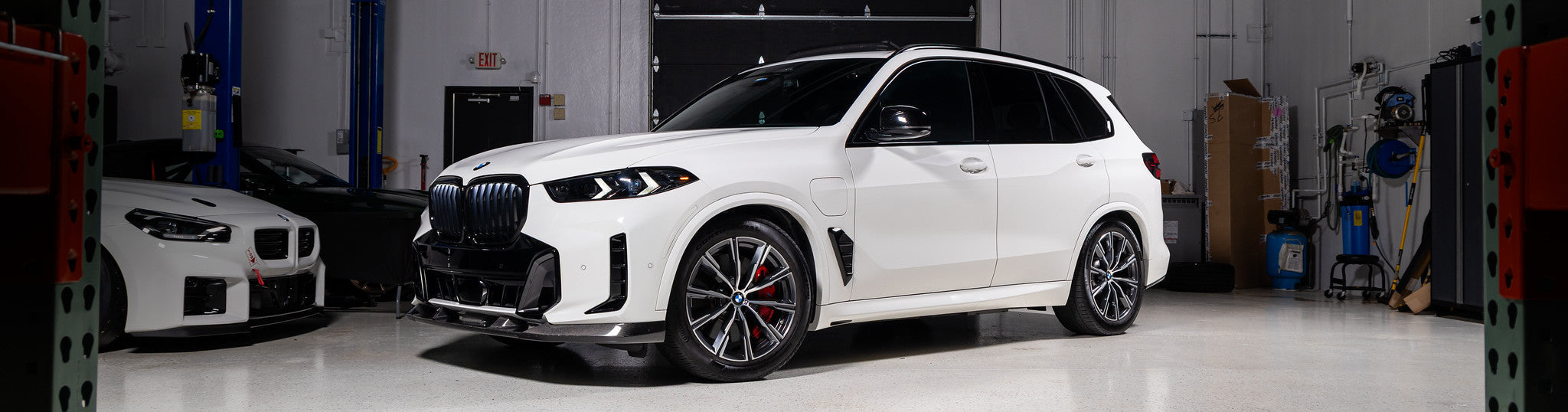 Alpine White BMW G05 X5 with Baan Velgen Airmatic Lowering Link Set installed, demonstrating reduced ride height and improved stance in the IND warehouse