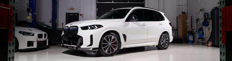 Alpine White BMW G05 X5 with Baan Velgen Airmatic Lowering Link Set installed, demonstrating reduced ride height and improved stance in the IND warehouse