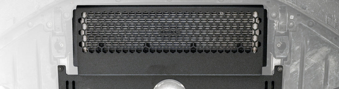 Close-up of the MMX Performance Oil Cooler Guard installed beneath a BMW G87 M2, showcasing the precision-formed 6061-T6 aluminum construction and optimized hexagonal grille protecting the factory S58 oil cooler.
