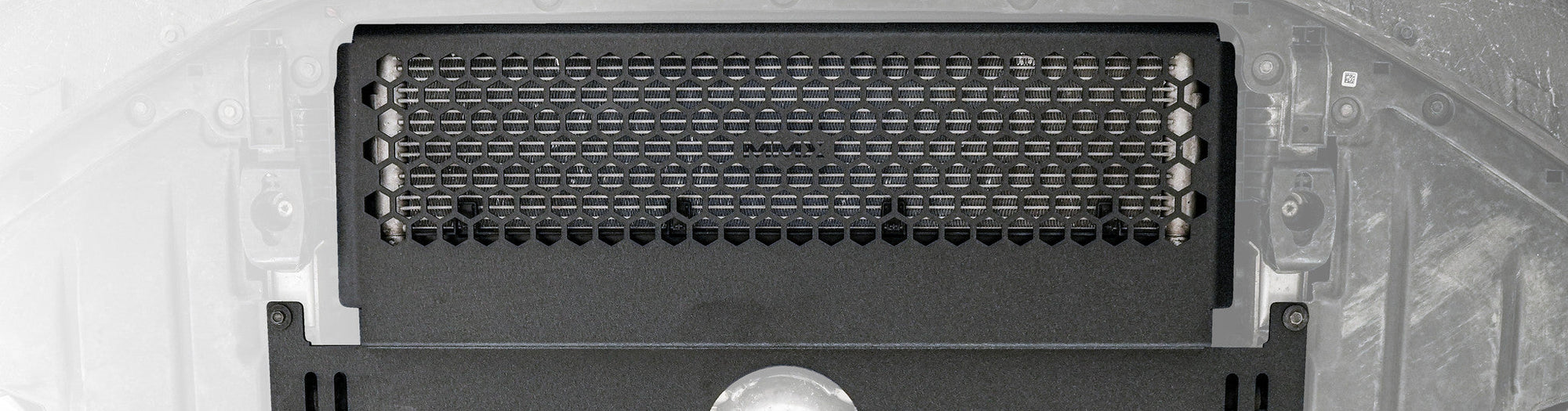 Close-up of the MMX Performance Oil Cooler Guard installed beneath a BMW G87 M2, showcasing the precision-formed 6061-T6 aluminum construction and optimized hexagonal grille protecting the factory S58 oil cooler.