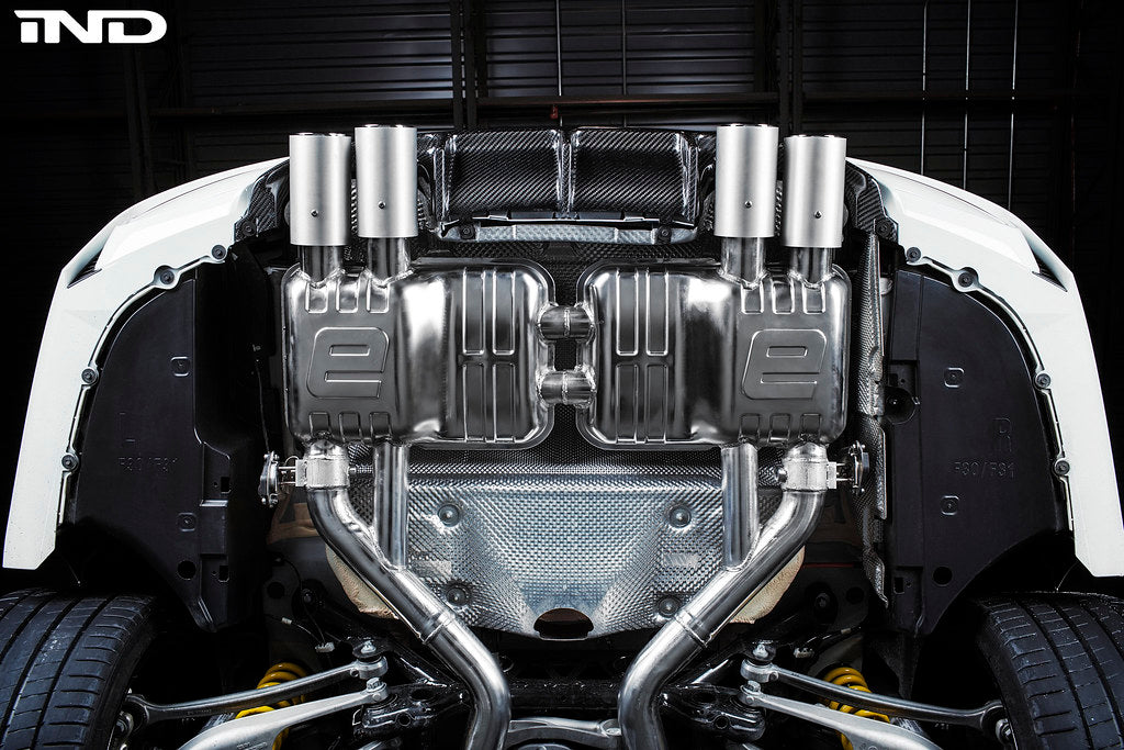 Eisenmann F8X M3 M4 performance exhaust system with valves, showing polished metal pipes and exhaust tips on a sleek vehicle.