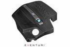 Black carbon engine cover for BMW F87 M2 N55 by Eventuri, with detailed carbon fiber weave and sleek exterior design.