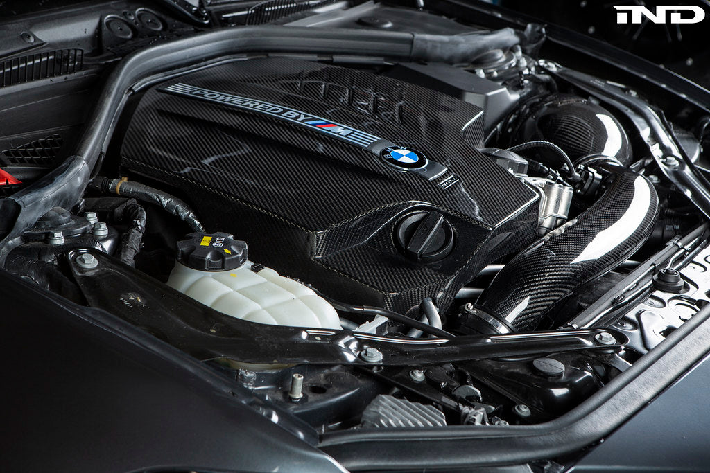 Black carbon engine cover for BMW F87 M2 N55 by Eventuri, exterior view showing sleek design and branding details.
