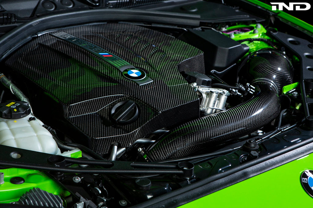 Black carbon engine cover for BMW F87 M2 N55 by Eventuri, exterior view showing sleek, high-performance design.