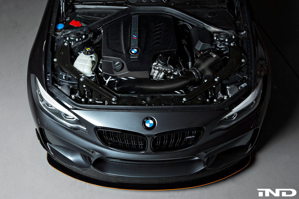 Black carbon engine cover for BMW F87 M2 N55 by Eventuri, showcasing sleek exterior design and high-quality craftsmanship.