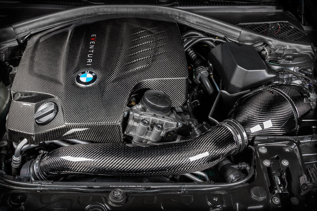 Eventuri black carbon engine cover for BMW F-Chassis N55 performance engine, showcasing sleek, lightweight design and branding details.