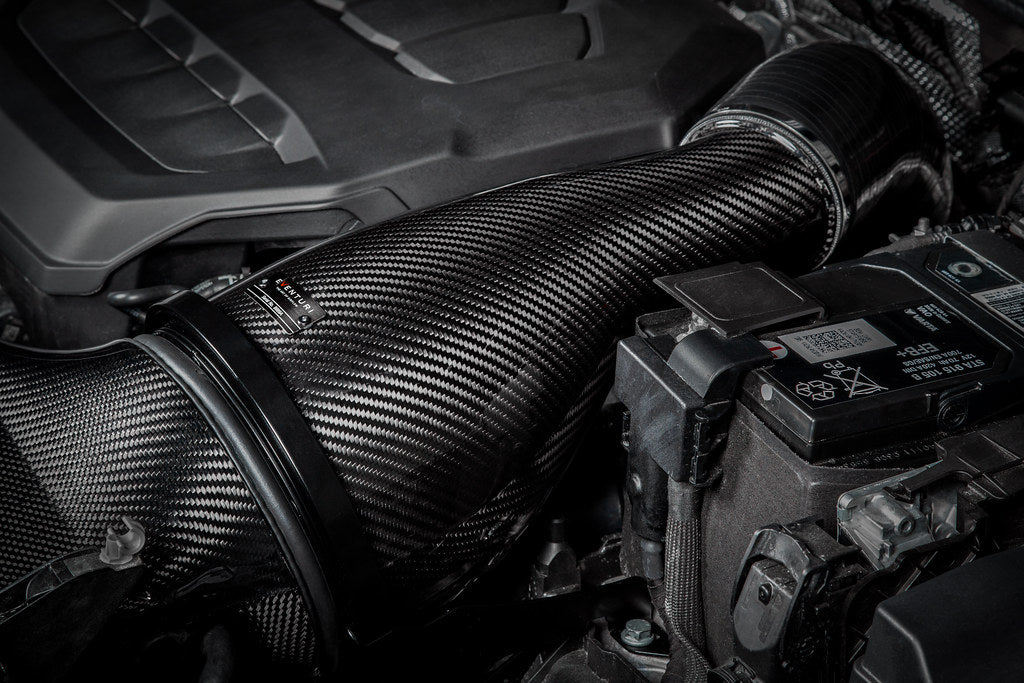 Close-up of a car engine with a carbon fiber air intake system.