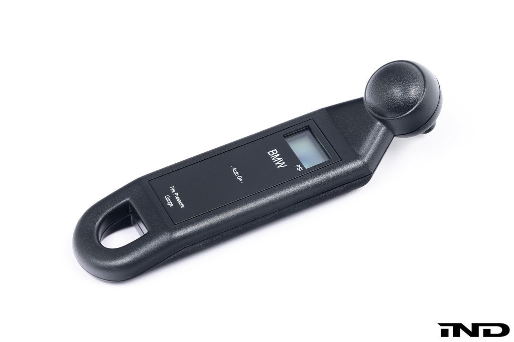 BMW electronic tire pressure gauge in a lifestyle setting, showing a compact digital display and ergonomic design.