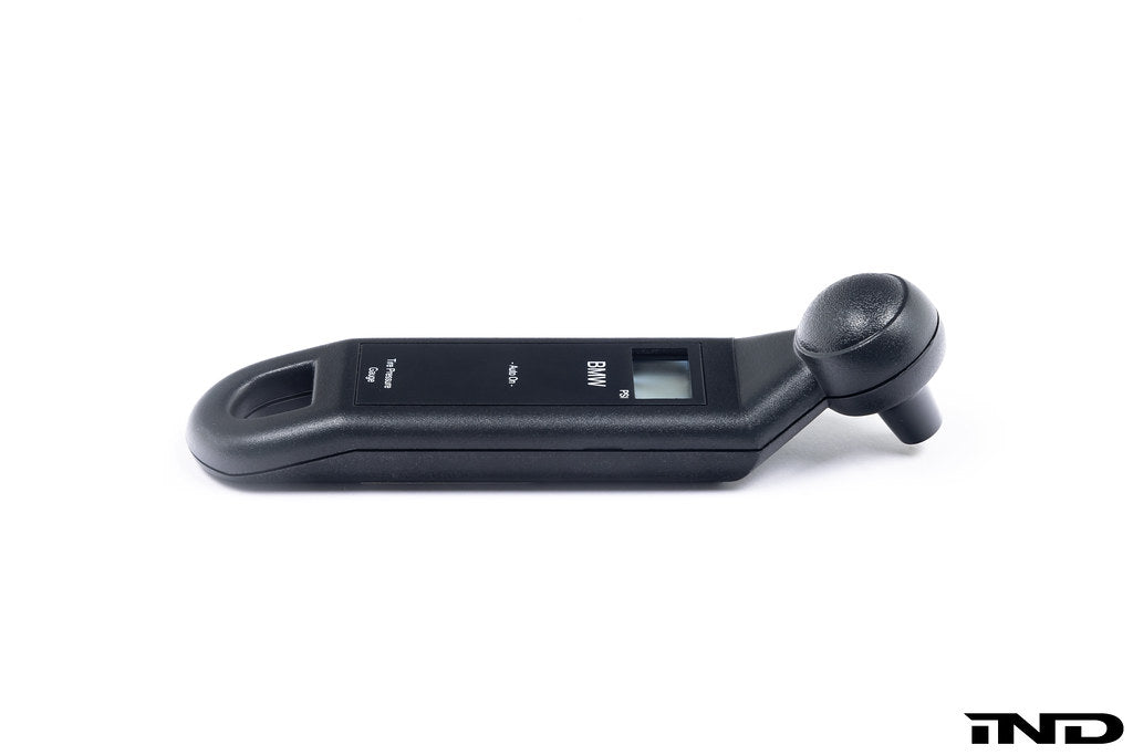 BMW electronic tire pressure gauge in a lifestyle setting, showcasing a compact digital device for accurate tire pressure measurement.