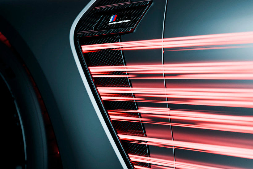 Close-up of a car's air vent with red light streaks, featuring a brand logo.