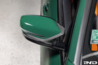 Alpha N G8X M2/M3/M4 carbon mirror cap set on exterior car side, showcasing sleek black finish and aerodynamic design.