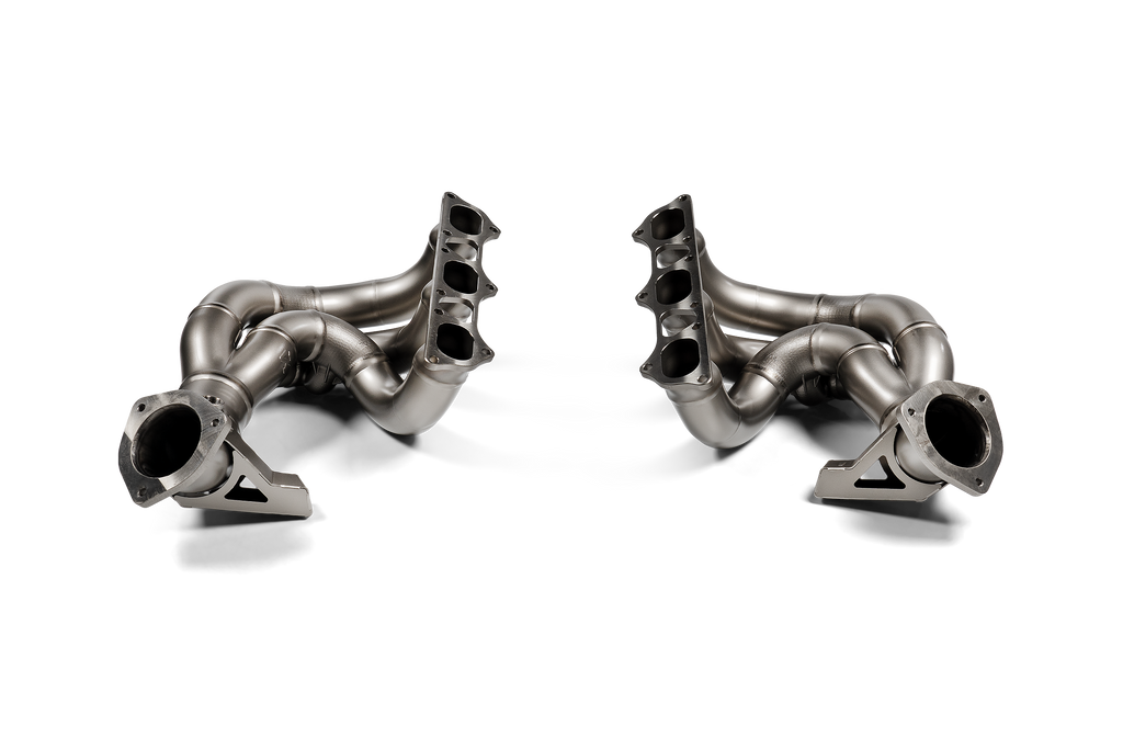 Akrapovic titanium exhaust header set for Porsche 718 Cayman GT4 RS and Spyder RS (982) models, showcasing sleek metallic design.