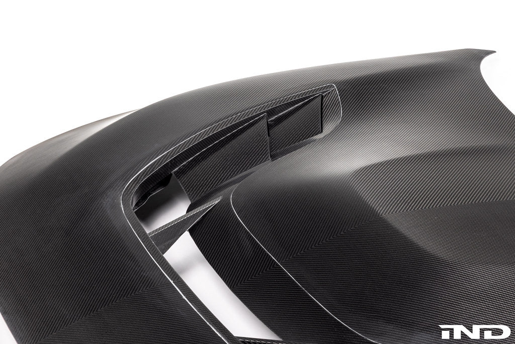 Alpha N F87 M2 Carbon Corse vented hood mounted on a car, featuring lightweight carbon fiber with a white background.