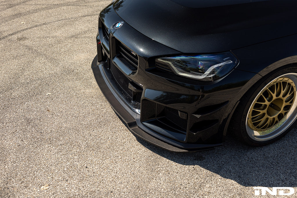 Alpha N G87 M2 carbon adjustable front lip installed on a vehicle, showcasing a sleek exterior upgrade with a Class 3 design.