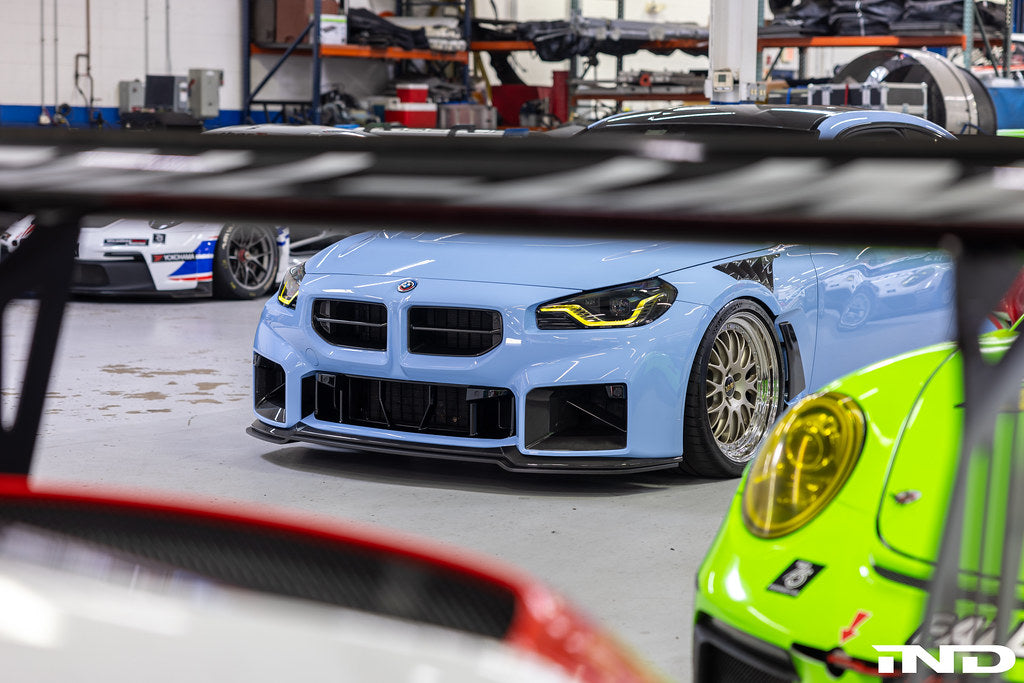 Alpha-N G87 M2 carbon adjustable front lip installed on a vehicle, showcasing its sleek exterior design and Class 3 style.