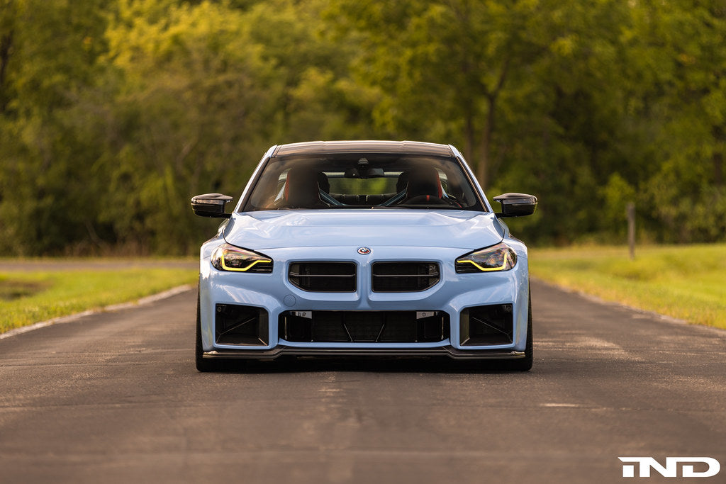 Alpha-N G87 M2 Carbon adjustable front lip installed on a vehicle, showcasing its sleek exterior design and Class 3 aerodynamic style.