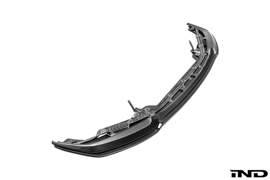 Alpha N G87 M2 carbon adjustable front lip, Class 3, mounted on a white background, showcasing its sleek exterior design.
