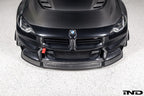 Alpha-N Carbon Corse front splitter installed on a Black Sapphire BMW G87 M2, enhancing the front-end appearance with pre-preg carbon fiber construction and aggressive styling.