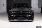 Alpha-N Carbon Corse front splitter installed on a Black Sapphire BMW G87 M2, enhancing the front-end appearance with pre-preg carbon fiber construction and aggressive styling.