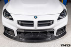 Alpha-N V2 Carbon Front Grille installed on an Alpine White BMW G87 M2, front view showcasing the aggressive motorsport-inspired design and exposed carbon fiber construction.
