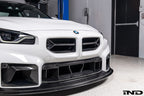Alpha-N V2 Carbon Front Grille installed on an Alpine White BMW G87 M2, front view showcasing the aggressive motorsport-inspired design and exposed carbon fiber construction.