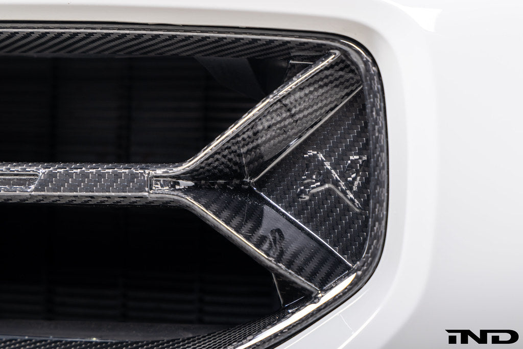 Alpha-N V2 Carbon Front Grille installed on an Alpine White BMW G87 M2, front view showcasing the aggressive motorsport-inspired design and exposed carbon fiber construction.
