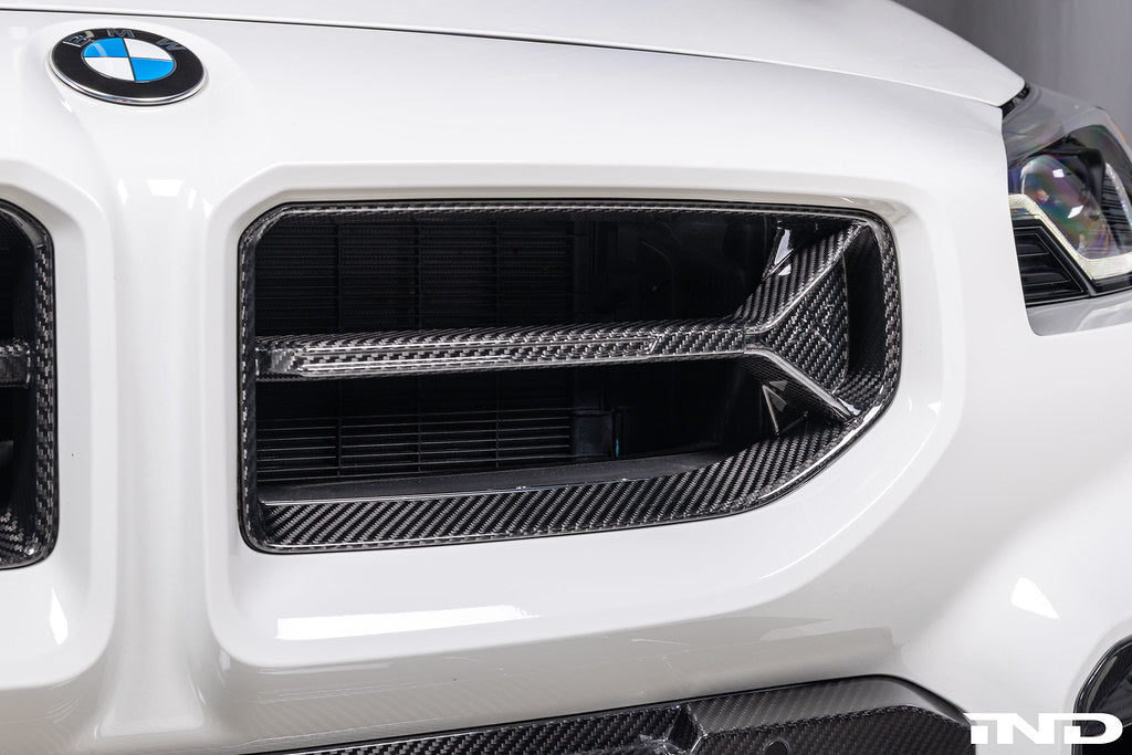 Alpha-N V2 Carbon Front Grille installed on an Alpine White BMW G87 M2, front view showcasing the aggressive motorsport-inspired design and exposed carbon fiber construction.