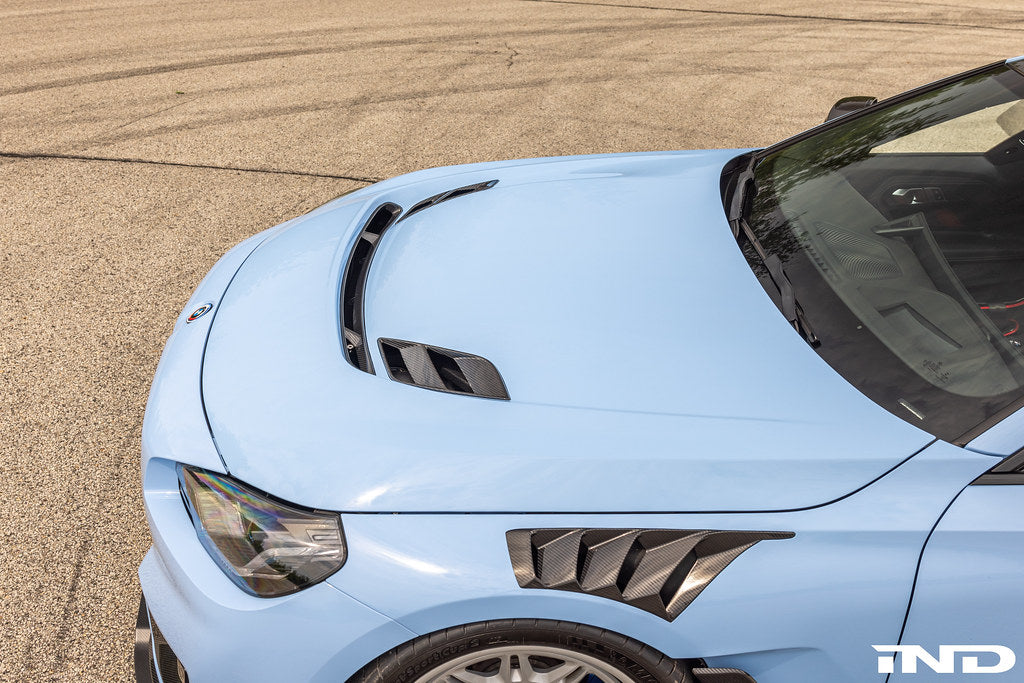 Alpha N G87 M2 carbon hood front vent insert installed on exterior of car, showcasing sleek carbon fiber design and precise fit.