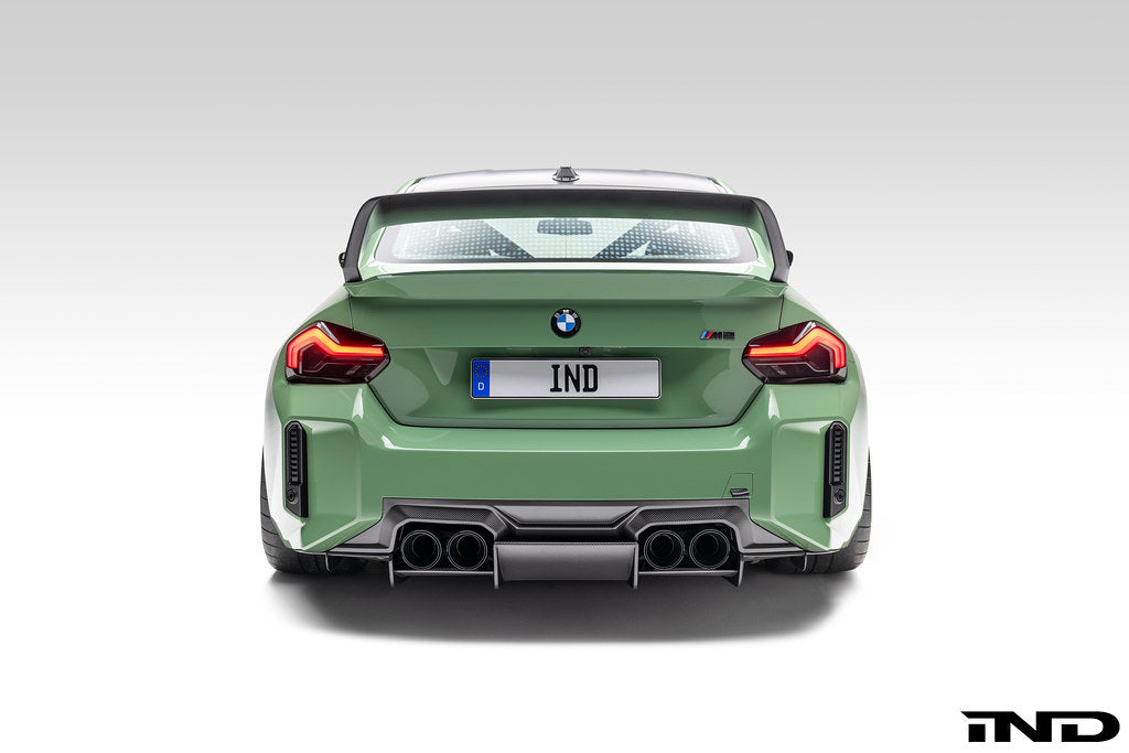 Alpha N G87 M2 carbon rear underbody floor kit installed on a vehicle, showcasing sleek carbon fiber exterior automotive upgrade.