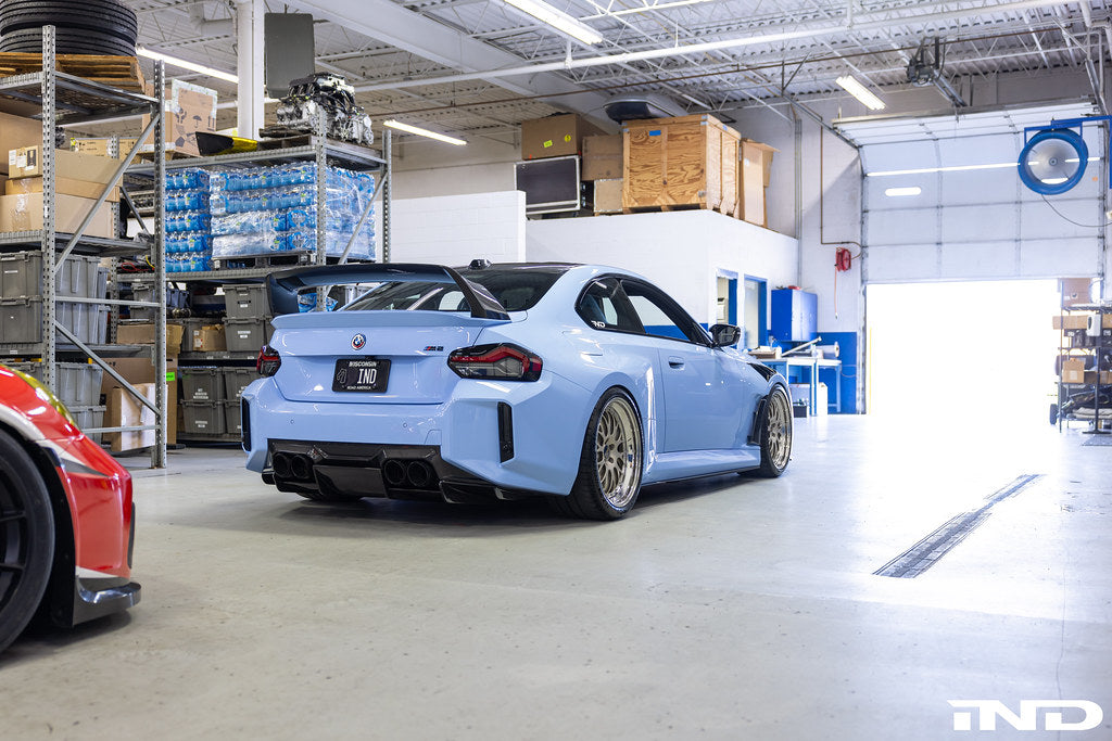 Alpha N G87 M2 carbon rear underbody floor kit installed on vehicle, showcasing sleek lightweight exterior upgrade.