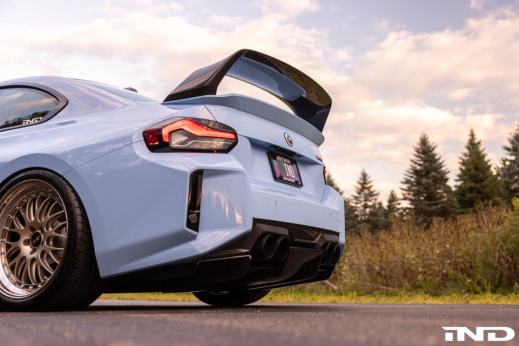 Alpha N G87 M2 Carbon rear underbody floor kit installed on a BMW M2, showcasing sleek carbon fiber exterior racing modification.