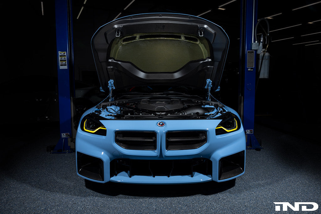 Alpha N G87 M2 carbon vented hood installed on a car, showcasing its lightweight, aerodynamic exterior design and venting features.