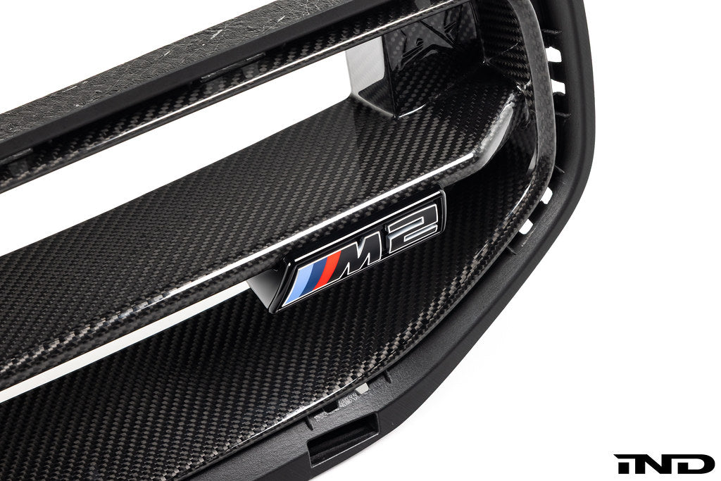 Alpha N G87 M2 LCI front grille emblem retainer with BMW OEM M2 badge installed on the vehicle exterior.