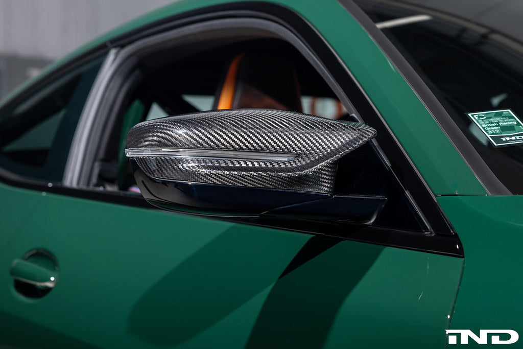 Alpha N G8X M2 M3 M4 carbon mirror cap set installed on a vehicle, showcasing sleek, lightweight exterior mirror covers.