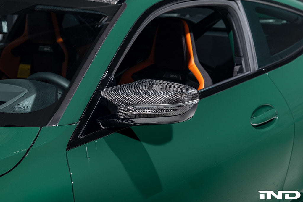Alpha N G8X carbon mirror cap set installed on M2, M3, or M4 exterior mirrors, showcasing sleek black carbon fiber design.