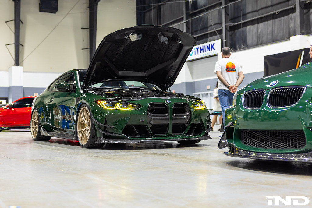 Alpha N G8X M3 M4 carbon front spoiler canard set installed on vehicle, showcasing sleek aerodynamic exterior upgrade.