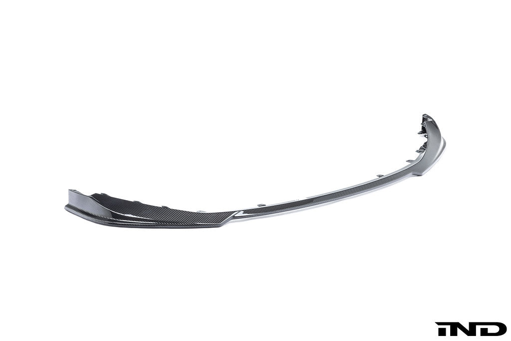 Alpha-N G8X M3 M4 carbon front spoiler installed on a vehicle, showcasing its sleek exterior design against a white background.