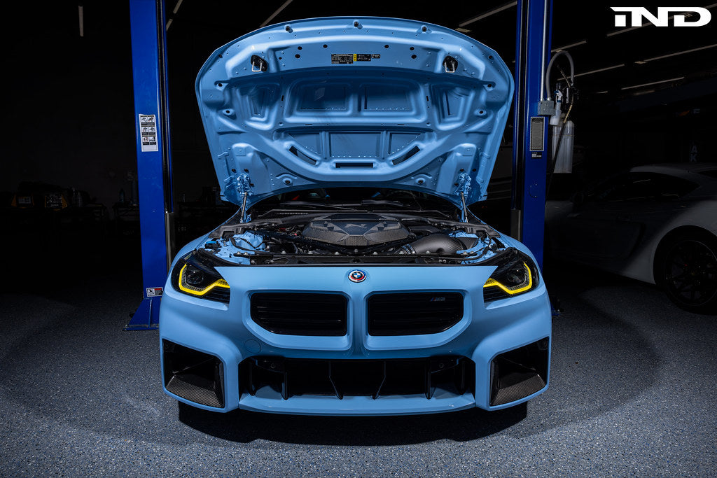 Alpha N G8X S58 carbon engine cover installed on a BMW M2, M3, or M4 exterior engine bay, showcasing sleek carbon fiber finish.