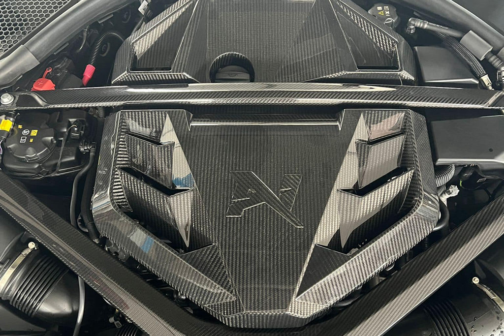 Alpha N G8X S58 carbon engine cover installed on BMW M2, M3, or M4 exterior engine bay, showcasing sleek black carbon fiber design.