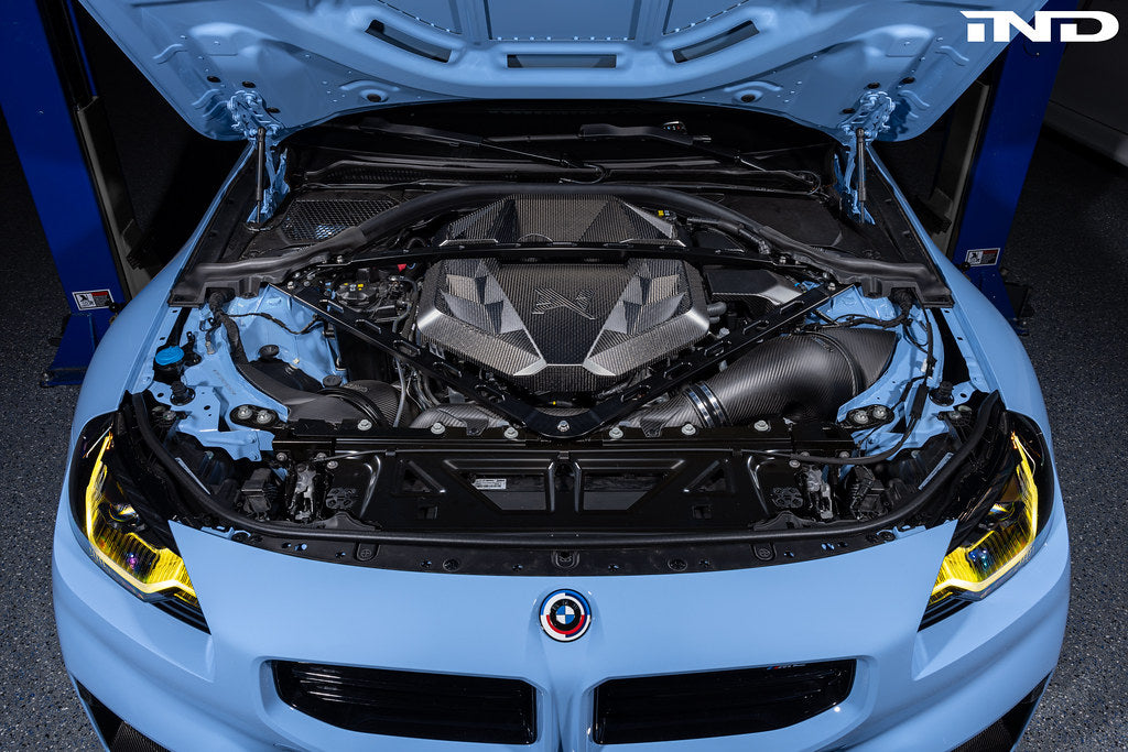 Alpha N G8X S58 carbon engine cover installed on exterior of BMW M2, M3, or M4 with sleek carbon fiber finish.
