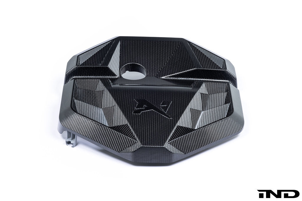 Alpha N G8X S58 carbon engine cover installed on a vehicle, exterior view with a white background, showcasing the sleek design.