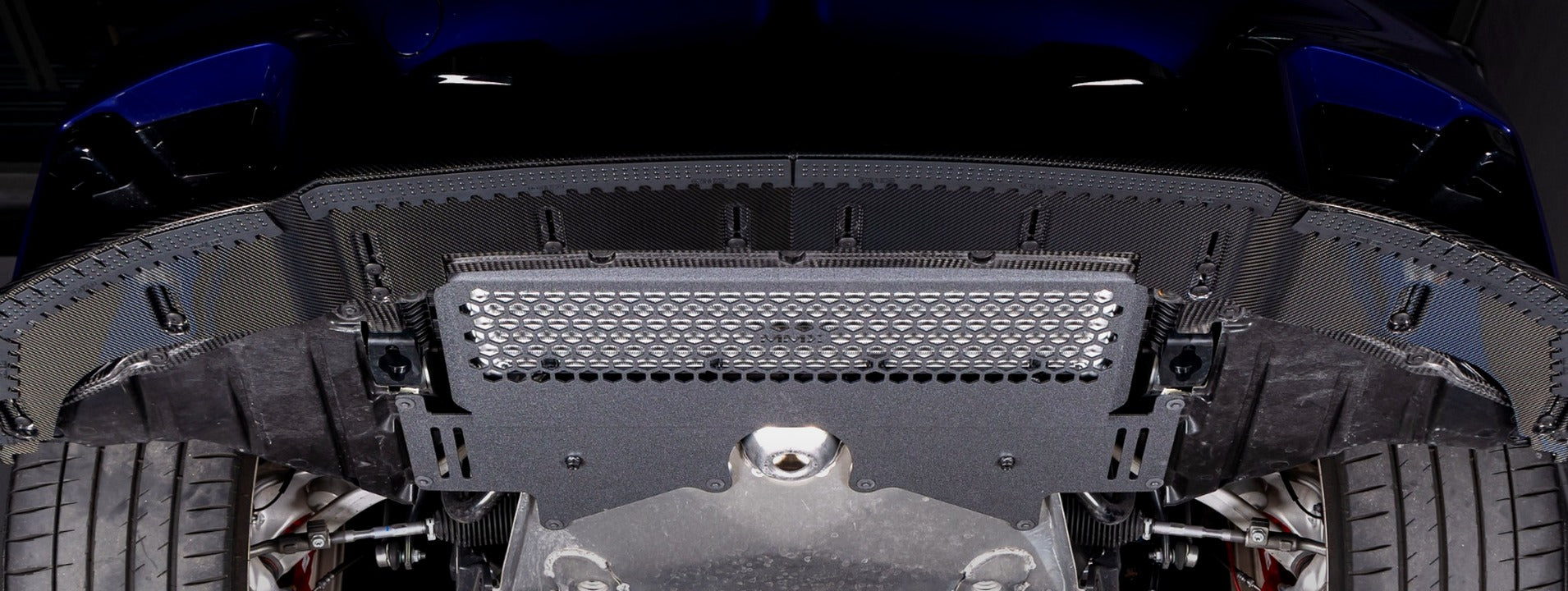 MMX Performance oil cooler guard installed on a BMW G87 M2 CS, highlighting the underbody protection and hexagonal grille design in a desktop hero image.