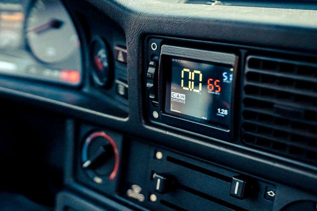 CANchecked MFD28 Gen2 2.8-inch multi-function display installed in the dashboard air vent of a left-hand drive BMW E28 M5 and 5-Series, displaying real-time vehicle data with OEM-style fitment.