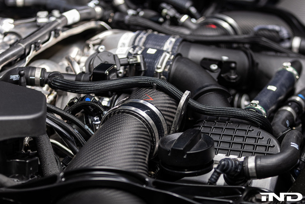 Close-up of Eventuri BMW G90 G99 M5 S68 carbon turbo inlet set in matte finish, installed on the engine for performance enhancement.