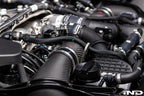 Close-up of Eventuri BMW G90 G99 M5 S68 carbon turbo inlet set in matte finish, installed on the engine for performance enhancement.