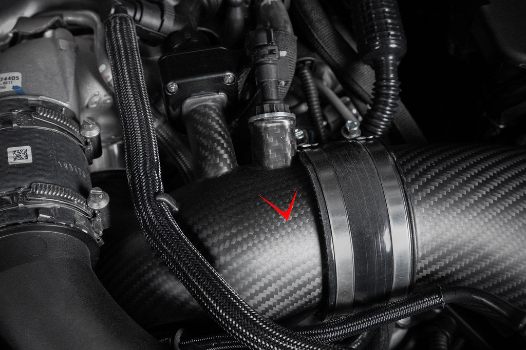 Close-up of matte carbon turbo inlet set installed on BMW G90 G99 M5 S68 by Eventuri, showcasing performance engine components.
